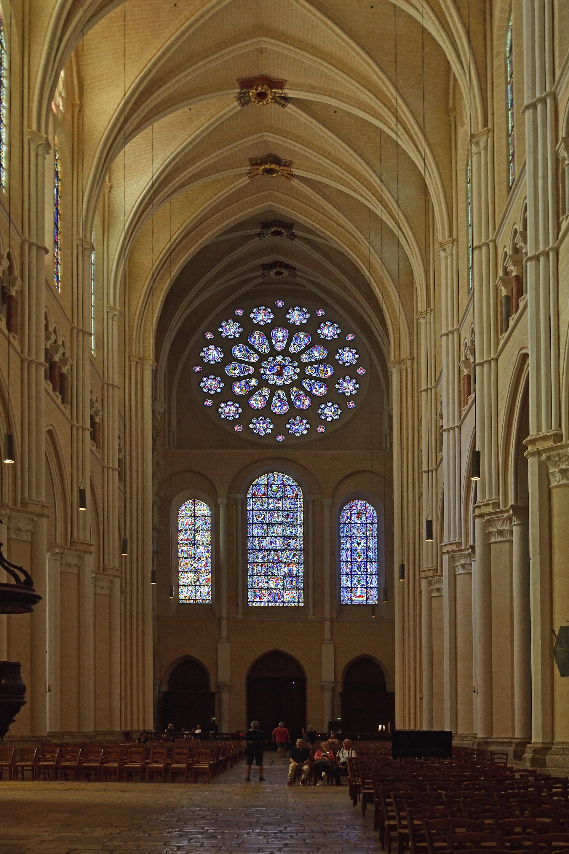 Interior de Chartres con pilares altos, bóvedas de crucería y vidrieras bajo un rosetón.